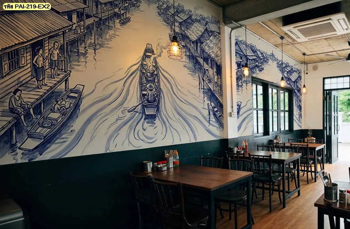 วอลเปเปอร์ลายตลาดน้ำไทย ภาพวาดเรือพายและบ้านริมน้ำที่เปลี่ยนผนังร้านให้มีเรื่องราว เข้ากับงานไม้และแสงไฟอบอุ่น